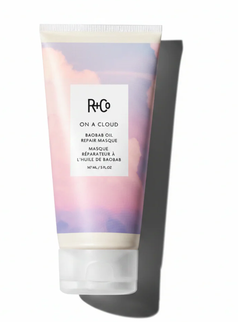 A squeeze tube of R+Co On A Cloud Baobab Oil Repair Mask, featuring a pastel sky design with purple, pink, and blue clouds, set against a white background with a soft shadow.